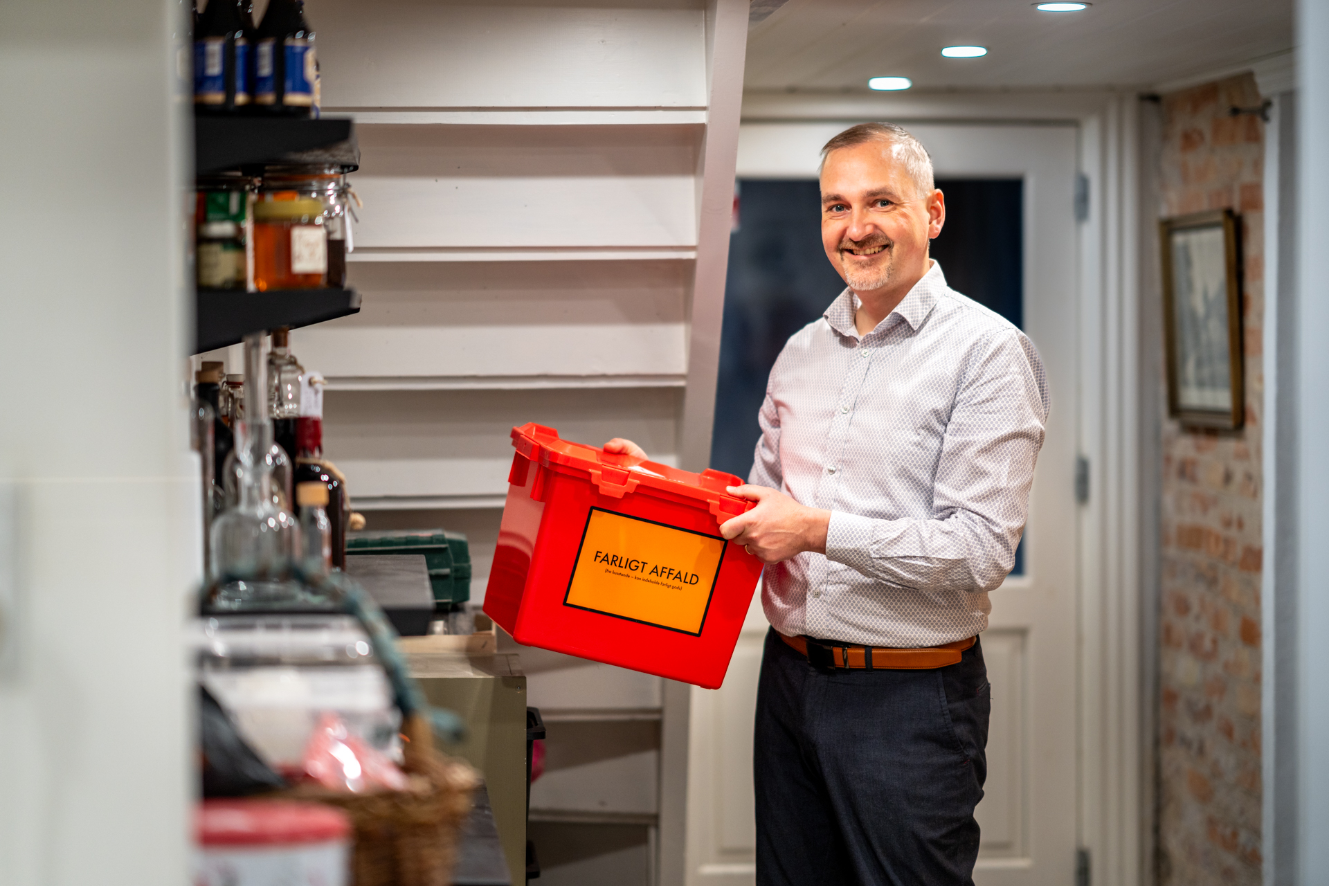 Henrik Müller, renosyds direktør i sin kælder. Han står med den røde kasse til farligt affald.